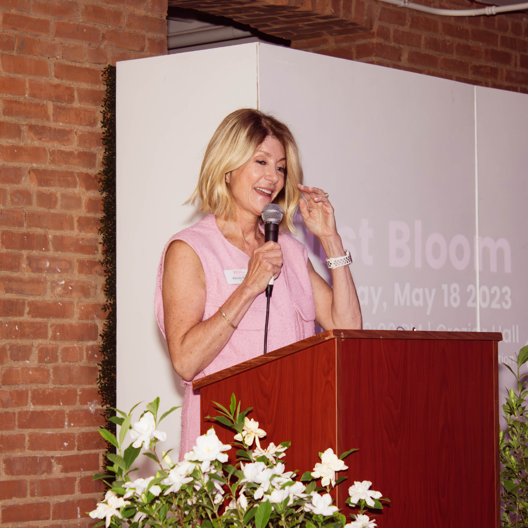 A picture of Wendy Davis in a pink dress speaking at a podium with a microphone in her hand.
